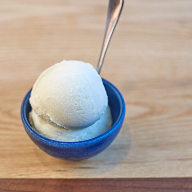 Înghețată de ardei negru cu frunze de dafin servită într-un castron albastru foarte mic pe o masă de lemn
